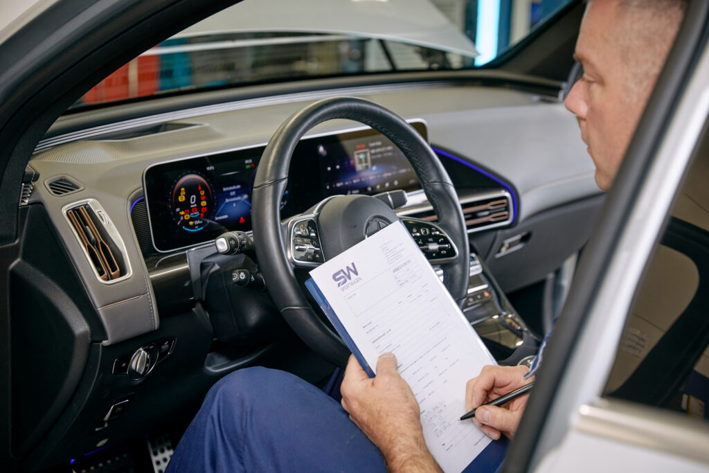 Mekaniker noterer i bilens førersete.